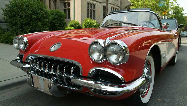 1959 Chevrolet Corvette C1 convertible, red classic car with chrome grille and whitewall tires, parked on a city street.