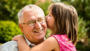 A picture of a granddaughter whispering into her grandfather's ear, to illustrate a PlannedGiving.Com post on Planned Giving Power Words That Work.