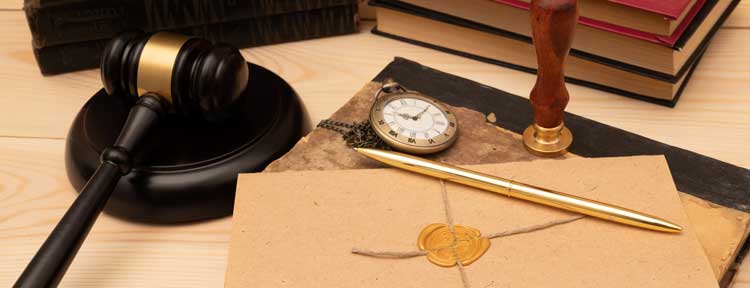 Gavel over legal documents and next to an old watch.