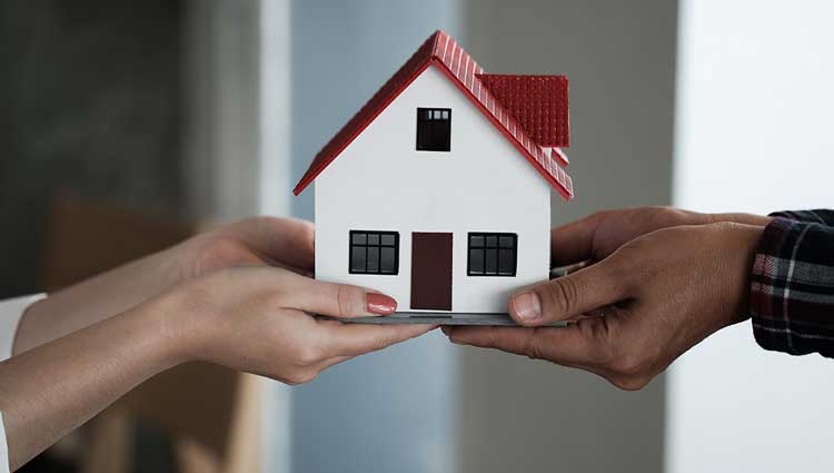 Hands holding a model house, symbolizing charitable real estate gifts to retirement home nonprofits.